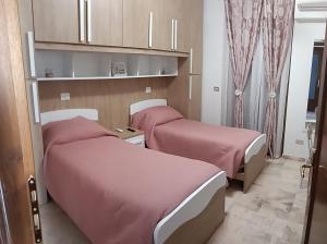 two beds in a small room with pink sheets at Beautiful Dreams in San Giorgio a Liri