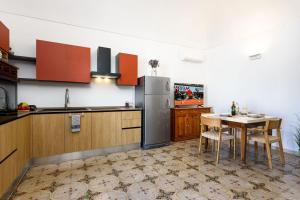 a kitchen with a table and a stainless steel refrigerator at Sinedda Sole in San Vito lo Capo