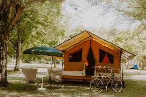 a tent with a bike parked in the grass at Camping Onlycamp Les Deux Rives in Lannion