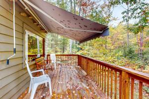 a porch with chairs and a table and an umbrella at Dragonfly Gully in Rhinelander