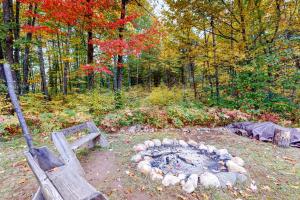 a fire pit in a park with a bench and trees at Dragonfly Gully in Rhinelander