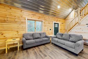 two couches in a room with wooden walls at Brown Bear Cabin in Tomahawk