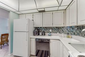 a kitchen with white cabinets and a refrigerator at Seaview Sunsets in Marco Island +34 photos