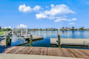 a dock on a lake with a blue sky and clouds at The Breezy Perch in Marco Island