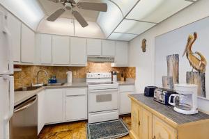 a kitchen with white cabinets and a bird on the counter at The Breezy Perch in Marco Island +31 photos