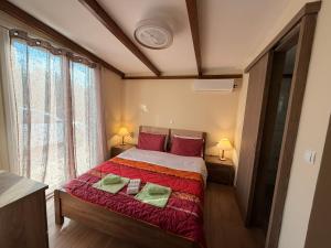 a bedroom with a bed with red pillows and a window at Villa Elena ΝΕΑΠΟΛΗ ΒΟΙΩΝ in Áyioi Apóstoloi