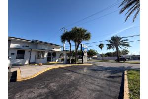 an empty street in front of a building with palm trees at Regency Inn Daytona Beach Near Airport in Daytona Beach
