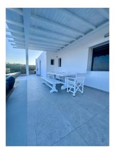 a white room with a table and benches in it at Psaros Village Mykonos in Platis Gialos