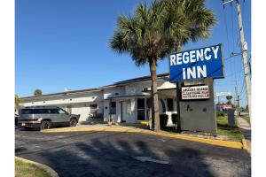a necessary inn with a palm tree in a parking lot at Regency Inn Daytona Beach Near Airport in Daytona Beach +184 photos