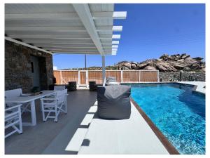 a patio with a table and chairs and a swimming pool at Psaros Village Mykonos in Platis Gialos