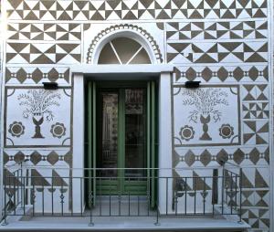 a building with a green door and a balcony at Mastiha Essence Residence in Pyrgi