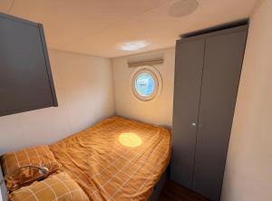 a small bed in a small room with a window at Glamping Houseboat in Dinteloord