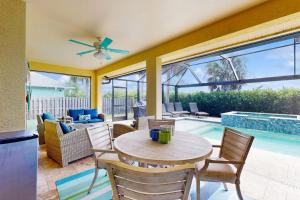a patio with a table and chairs and a pool at The Sunshine Social in Naples