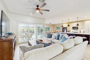a living room with white furniture and a ceiling fan at The Sunshine Social in Naples