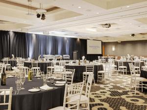 a conference room with tables and chairs and a screen at Novotel Wollongong Northbeach in Wollongong +144 photos