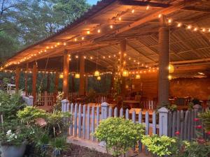 a wooden pavilion with lights and a white fence at Sunshine Resort & Spa Sigiriya in Sigiriya