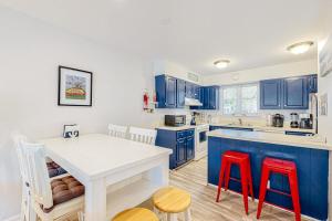 a kitchen with blue cabinets and a white table and red chairs at Sea Colony --- 3404 Round Robin Way in Bethany Beach