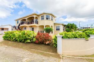 a large yellow house with plants in front of it at Oceanview Terrace, Walk to Beach, WiFi and Parking in Saint Lucy