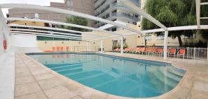 a large swimming pool with orange chairs and a building at Los Sauces Hotel & Spa in Villa Carlos Paz