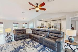 a living room with a leather couch and a ceiling fan at Cocktail Cove in Cape Coral