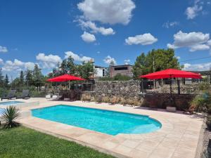 a swimming pool with red umbrellas in a yard at Terrazas de la Quinta - Cabañas de Montaña in Mendoza