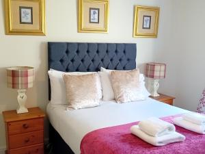 a bedroom with a large white bed with two lamps at Abbeyside Cottage in Kelso