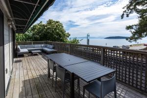 a wooden deck with a table and chairs and the water at Sechelt inn in Sechelt
