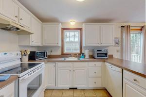 a white kitchen with white cabinets and a sink at Skylight Tonight in South Dennis