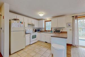 a kitchen with white cabinets and a white refrigerator at Skylight Tonight in South Dennis