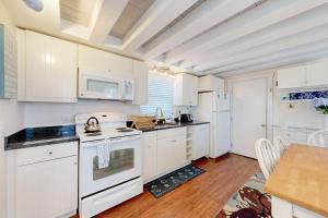 a kitchen with white cabinets and a white stove top oven at Oak Bluffs Cottage in Oak Bluffs +18 photos
