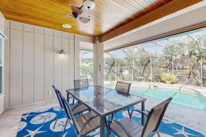 a dining room with a table and chairs and a swimming pool at Tranquil Haven in Marco Island