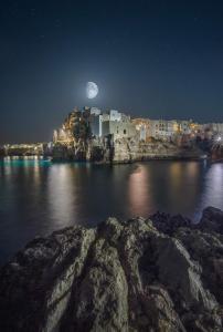 a view of a city at night with the moon at Casa Nannì in Polignano a Mare +16 photos