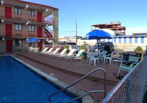 a pool with chairs and umbrellas next to a building at Cloud 9 Inn - Beach Hotel in Seaside Heights