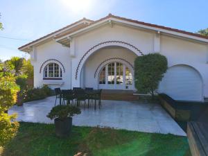 a white house with a table and chairs at Belle maison basco landaise avec jacuzzi in Labenne