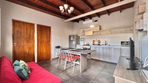 a kitchen with a red couch and a table at Terrazas de la Quinta - Cabañas de Montaña in Mendoza