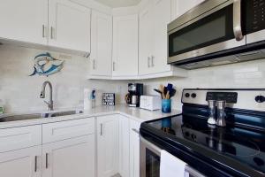 a kitchen with white cabinets and a black stove top oven at Southwest Florida Sanctuary in Cape Coral