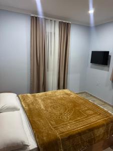 a bedroom with a bed with a gold blanket on it at Imperio Boge Hotel in Bogë