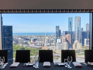 a table with wine glasses and a view of the city at Sofitel Melbourne On Collins in Melbourne