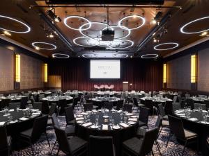 a conference room with tables and chairs and a projection screen at Sofitel Melbourne On Collins in Melbourne
