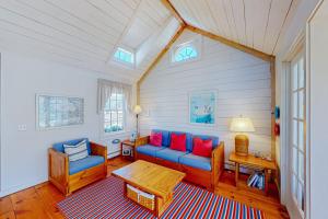 a living room with a blue couch and red pillows at Maushop By The Sea in Mashpee