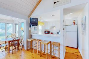 a kitchen with a table and chairs and a refrigerator at Maushop By The Sea in Mashpee