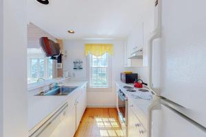 a white kitchen with a sink and a refrigerator at Maushop By The Sea in Mashpee +14 photos