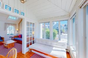 a living room with a white couch and windows at Maushop By The Sea in Mashpee