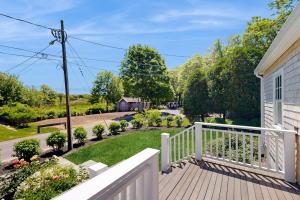 a porch of a house with a white railing and a yard at Blissful Island Haven in Oak Bluffs