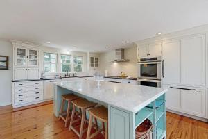 a large kitchen with white cabinets and a blue island at Blissful Island Haven in Oak Bluffs +17 photos