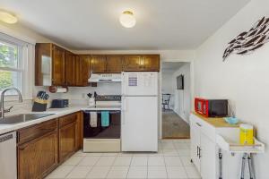 a kitchen with a white refrigerator and wooden cabinets at Great Pond Escape in Falmouth +18 photos