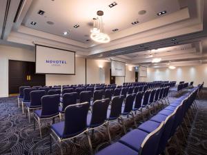 a conference room with rows of chairs and a screen at Novotel Melbourne Glen Waverley in Glen Waverley +59 photos