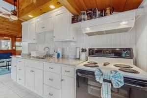 a kitchen with white cabinets and a stove top oven at Glendon Beach Getaway in Dennis +11 photos