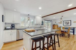 a kitchen with white cabinets and a counter with bar stools at The Blue Whale Cottage in Brewster