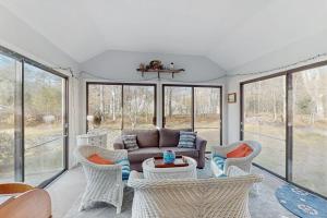 a living room with a couch and chairs and windows at The Blue Whale Cottage in Brewster +16 photos